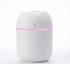White essential oil diffuser with a pink light on a white background