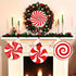 Decorative Christmas wreath with candy cane patterns on a fireplace mantel.