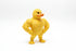 Muscular yellow rubber duck standing on a concrete surface with grass in the background
