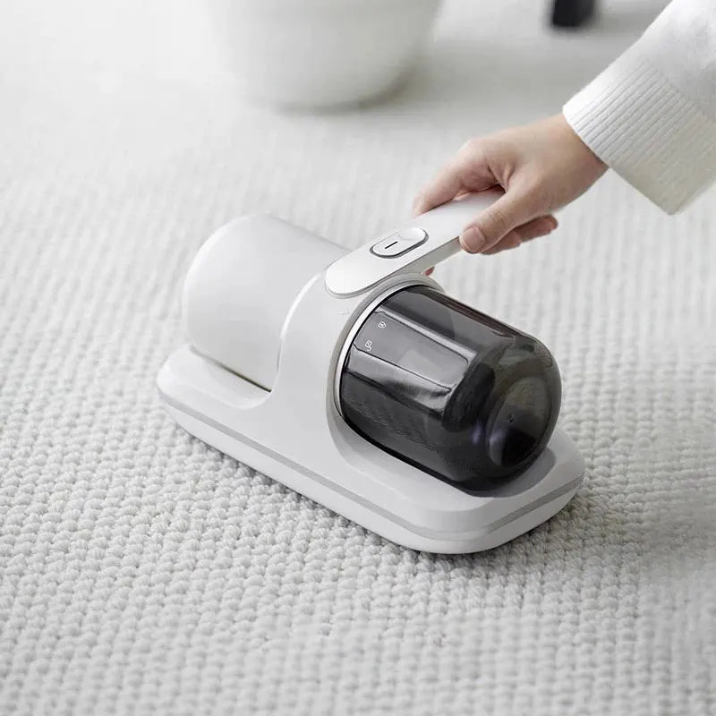Hand using a handheld vacuum cleaner on a light-colored surface