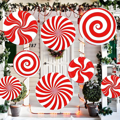 Red and white candy cane decorations on a door with Christmas trees and lights.